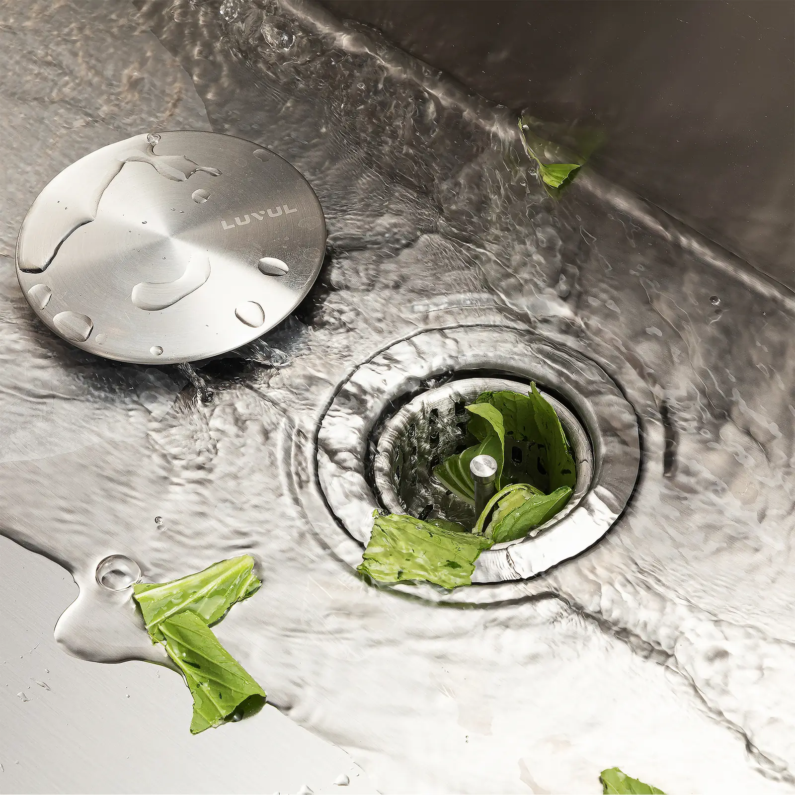 LUVUL strainer lid resting beside the drain while water flows over a stainless sink floor