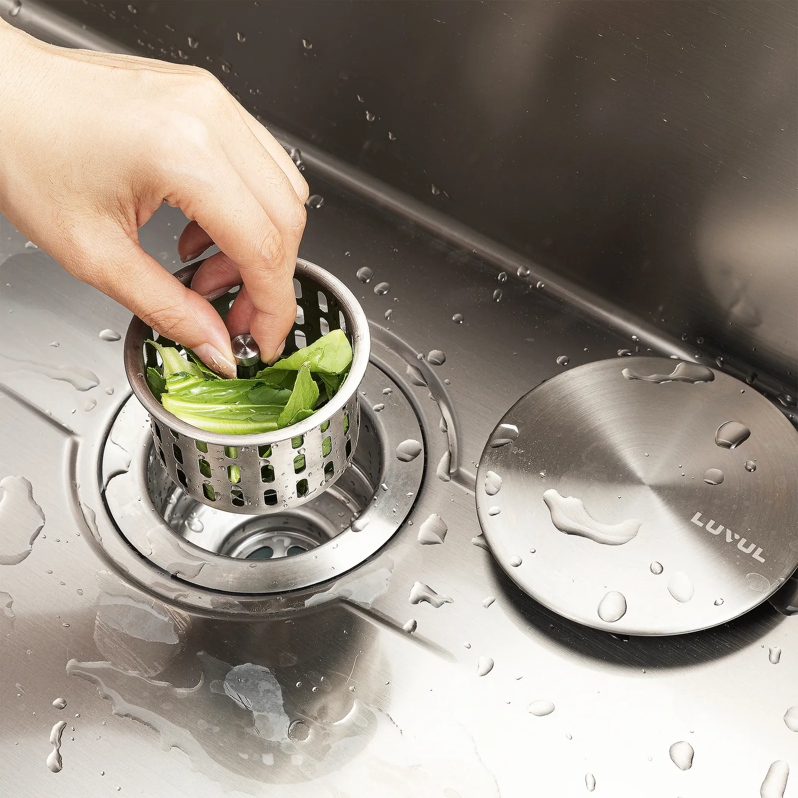 Hand lifting the LUVUL strainer basket with vegetable scraps out of the drain